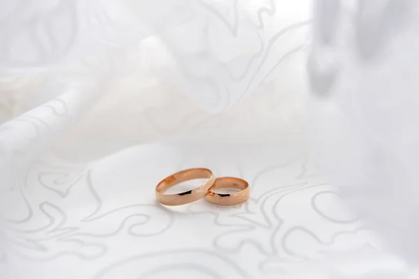 Classic wedding rings lie on the light satin fabric. Wedding rings on the photo for the template under the text