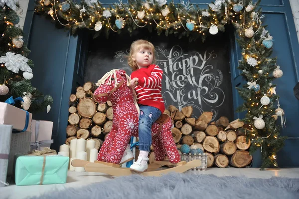 Маленька Дівчинка Сидить Червоному Коні Фоні Різдвяного Інтер Єру Каміном — стокове фото