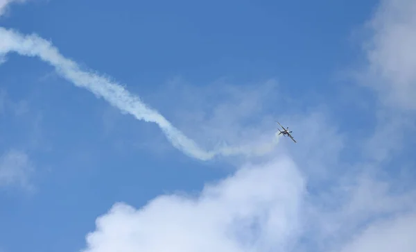Light piston aircraft flies during an air show in a beautiful sky with clouds