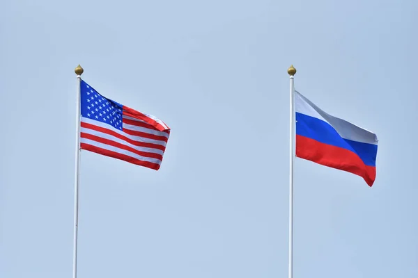 Beautiful and bright flags of the Russia and the United States of America against the sky. Flags of Russia and America as a symbol of cooperation and friendship