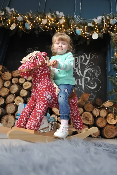 Маленька Дівчинка Сидить Червоному Коні Фоні Різдвяного Інтер Єру Каміном — стокове фото