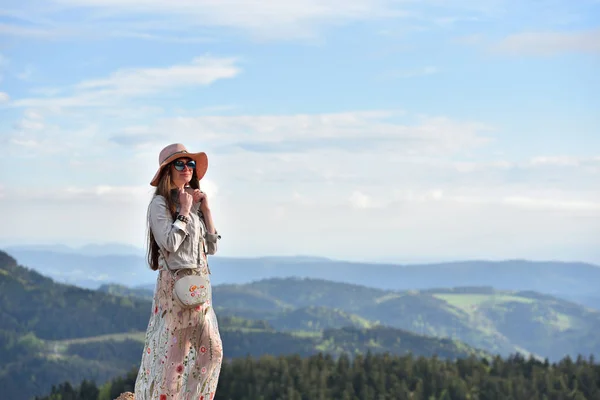 穿着粉色衣服 头戴粉色帽子 美丽而年轻的女游客站在施瓦茨瓦尔德的天空和群山中 — 图库照片