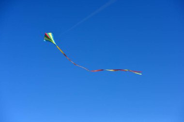 Güneşli bir günde açık ve mavi gökyüzünde uçan uçurtma.