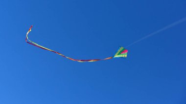 Güneşli bir günde açık ve mavi gökyüzünde uçan uçurtma.