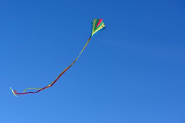 Güneşli bir günde açık ve mavi gökyüzünde uçan uçurtma.