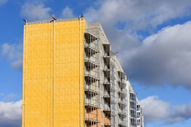 Konut inşaatı ve dış duvarların özel ısı yalıtımlı malzemelerle yalıtımı. Mavi gökyüzüne karşı termal yalıtımlı duvar.