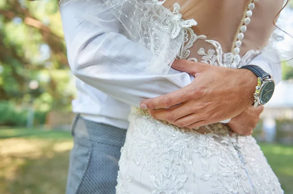 Groom hugging the bride by the waist, closeup hands