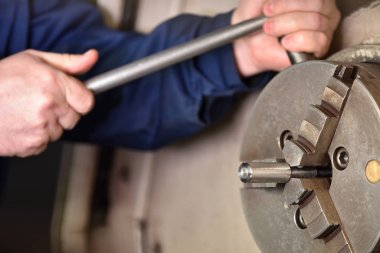 İşçi, Cnc makinesini işlemek için yeni metal parçaları yüklüyor. İşçinin elleri makineyi kapatıyor, bağlıyor ve işlemek için detay oluşturuyor.