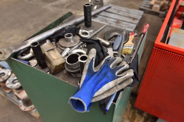 Kirli mavi eldivenler fabrikadaki aletlerin yanında yatıyor..