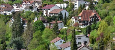 Almanya 'da bir yamaçta şirin bir köy, ormanın arka planında apartmanlar.