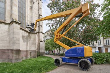 Yükselmek için özel bir makine. Bir işçi, Evanjelik Kilisesi 'nin eski binasını yüksek irtifada restore ediyor.