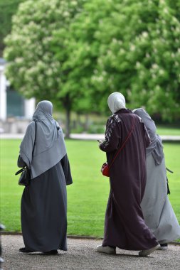 Avrupa parkında başörtüsü içinde yürüyen üç kadın mülteci. Almanya, Baden Baden