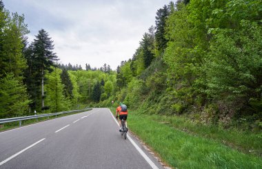 Ormanda virajlı otoban ve bisikletçiler yol boyunca gidiyor. Schwarzwald Ormanı Yolu ve Bisikletçi. Almanya 