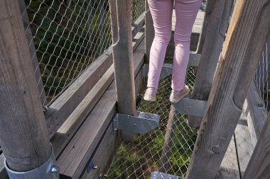 Turist kız eğlence dolu ahşap bir köprüde Alman ormanında Schwarzwald köprüsünün şeffaf zemininde koşuyor.