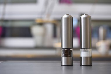 Güzel metal biber karıştırıcı ve tuzluk, en popüler baharatlar, mutfaktaki masada siyah biber ve tuz.