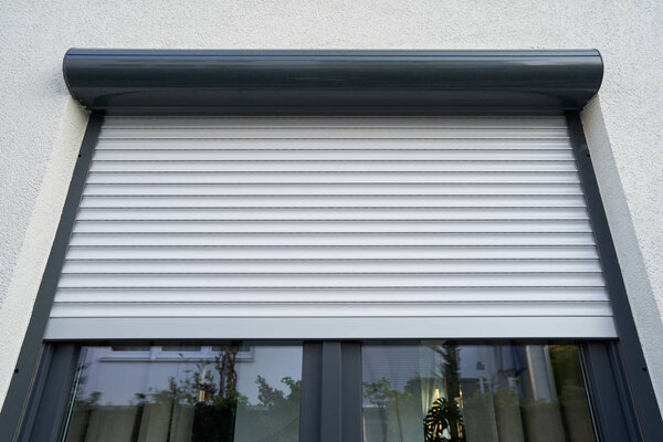 Light roller shutter curtains mounted on a dark window