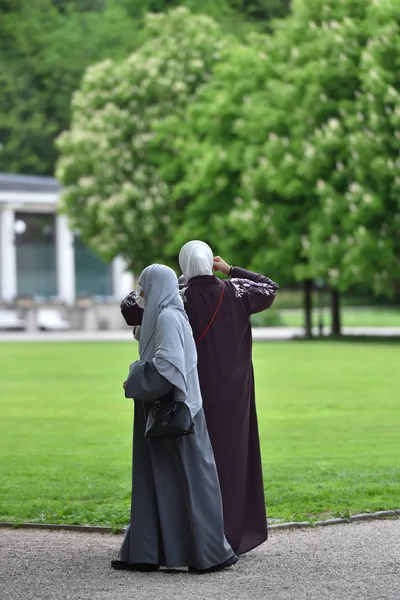 Two women refugees walking in hijabs in the European park. Germany, Baden Baden