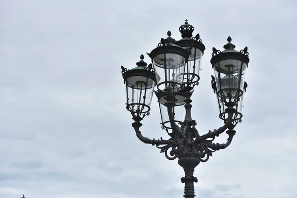 Beautiful classic iron lamppost of six lamps with diode bulbs against a cloudy sky in a European city — Stock Photo, Image