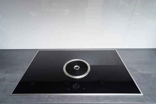 Induction cooker with black glass surface and integrated cooker hood