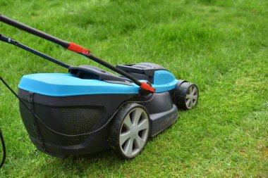 Elektrikli çim biçme makinesi parlak yeşil bir çim biçer, yakın plan.