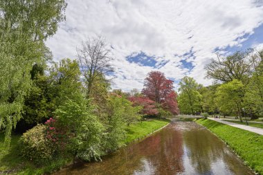 Dar bir nehir, ağaçlar ve Avrupa 'nın Baden şehrinde halka açık bir parktaki demir köprü manzarası.