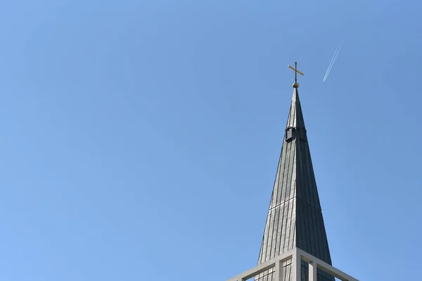 Tower with a cross and a clock against a blue sky with a flying airplane, with text space in the European city of Pforzheim, Germany