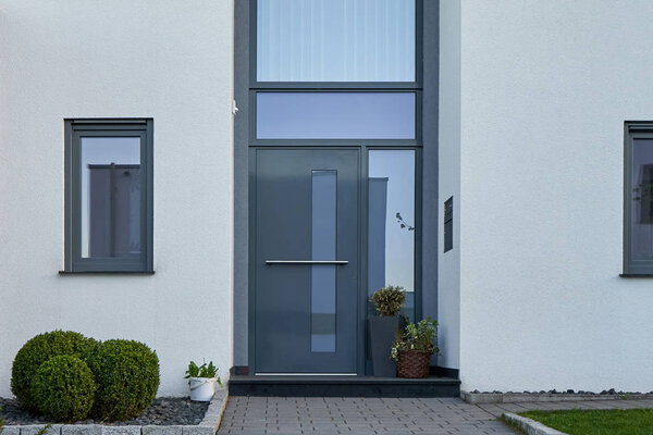 Facade of a modern house with a gray front door and flowers.