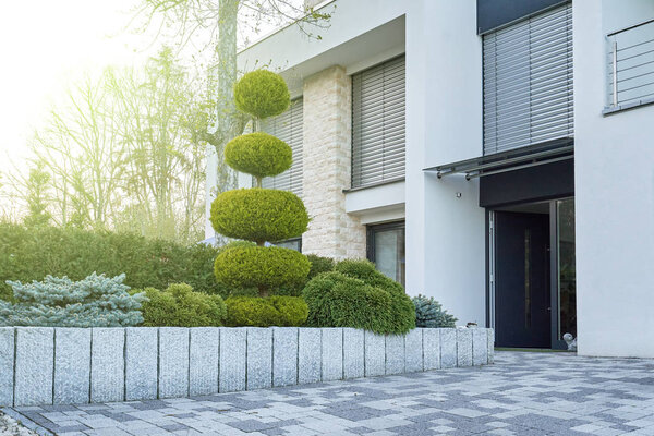 PFORZHEIM, GERMANY - APRIL 21ST, 2019: Flowerbed with conifers near the entrance to the modern house.