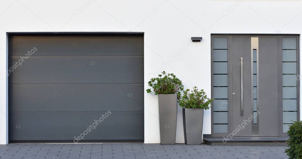 Modern gray garage, next to the Scandinavian-style house. Private garage with automatic door in a European