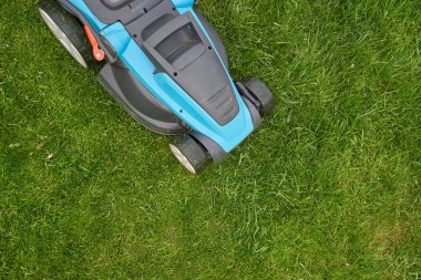 Elektrikli çim biçme makinesi parlak yeşil bir çim biçer, yakın plan.