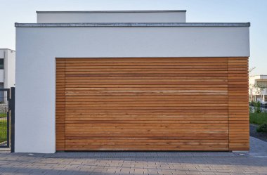 Ahşap panelli garaj kapısı olan modern İskandinav tarzı bir garaj. Avrupa şehrinde otomatik kapısı olan özel bir garaj.