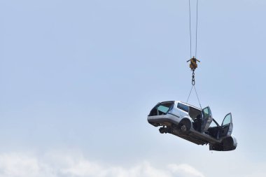 Tekerlekleri olmayan eski bir araba, geri dönüşüm öncesi, metin alanı olan bir kabloyla gökyüzüne kaldırılmış. Araba güncellemeleri, tüketim, yaşlılık, faydasızlık kavramı.