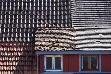 Eski bir evin çatısı farklı türde fayanslarla kaplıdır ve üzerinde yosun yetişir. Çeşitlilik ve karışım kavramı