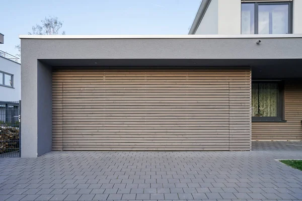 A modern Scandinavian-style garage with a wood-paneled garage door. Private garage with automatic door in a European city