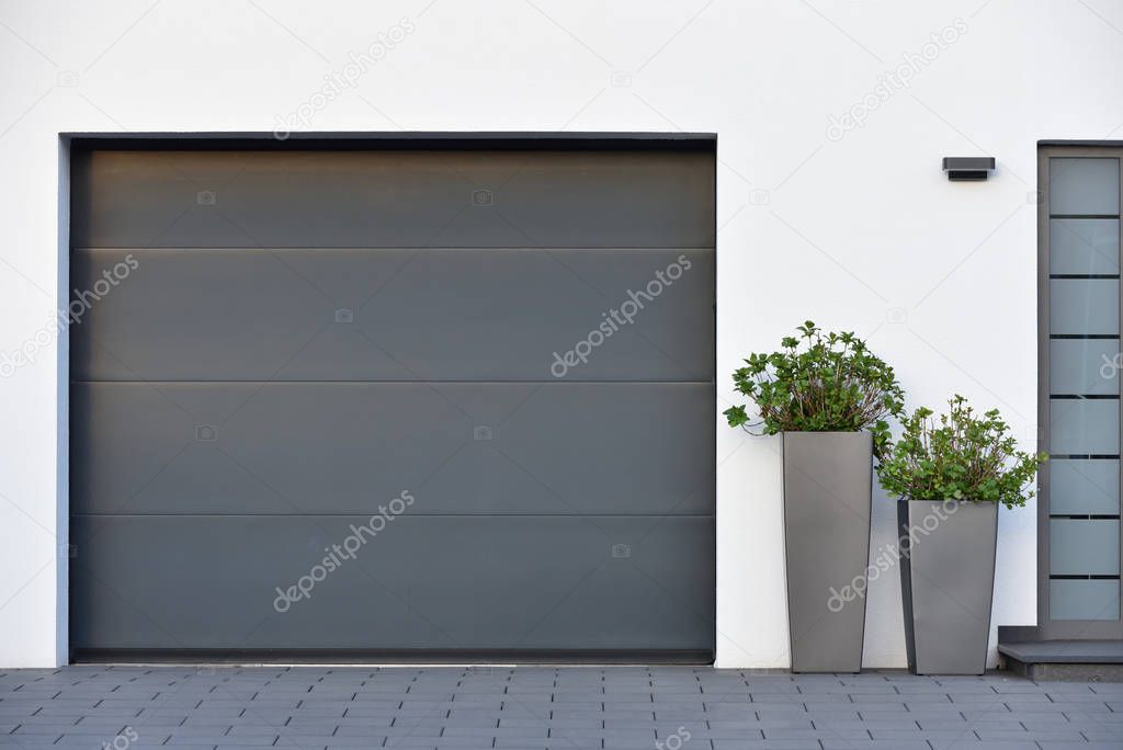 Modern gray garage, next to the Scandinavian-style house. Private garage with automatic door in a European