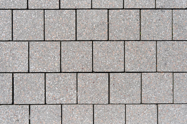 The texture of the square tiles of the sidewalk in gray in a European city