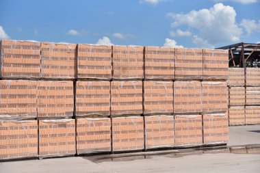 Yeni tuğlalar mavi gökyüzüne karşı fabrikanın açık hava deposunda duruyor..