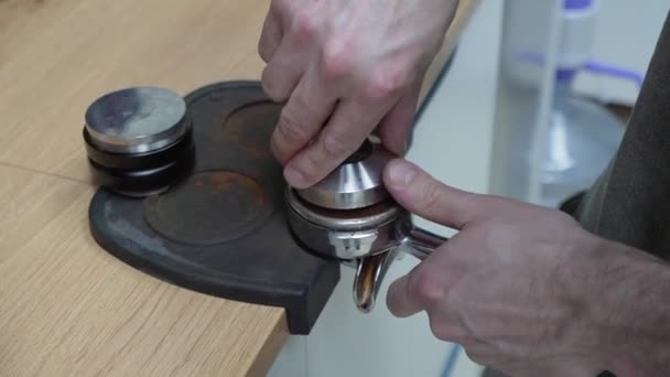 Barista makes coffee and holds a portafilter in her hands and presses coffee. — Stock Video