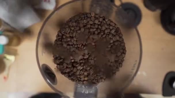 Koffiebonen vallen langzaam in een koffiemolen. Bovenaanzicht, close up. — Stockvideo