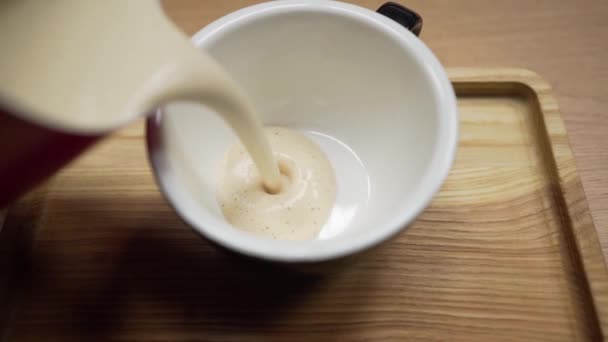 Barista gör kaffe och häller en tjock och fräsch dryck i en mugg. Händer och mugg med kaffe närbild — Stockvideo