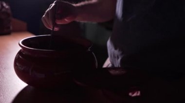 Erkek aşçı kaşığı sıcak şurupla karıştırır, görünür sıcak buharla.