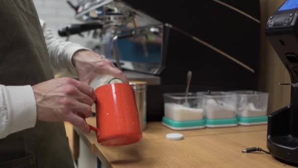 Bir barista adamı kahve hazırlar ve bir fincana süt döker ve kahve makinesinde buharla çırpar. Yakın plan. — Stok video