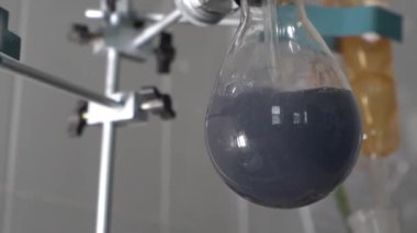 Laboratuvardaki araştırma sırasında cam test tüpünde kaynamış gri sıvı. Yakın plan.