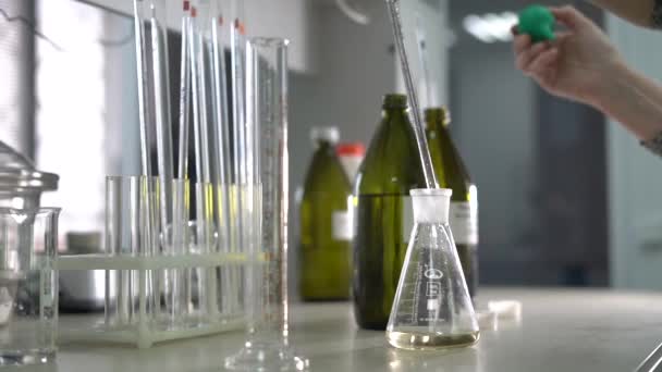 Laboratorium voor analyse in de fabriek. Een vrouwelijke laboratoriumassistent mengt vloeistoffen in een glazen kolf. Close-up. — Stockvideo