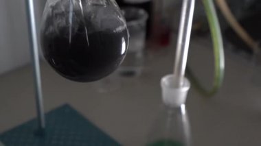 Laboratuvardaki araştırma sırasında cam test tüpünde kaynamış gri sıvı. Yakın plan.