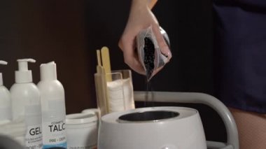 Depilasyon ustası kasede ısınmak için sert balmumu döker. Ağda ve şeker yapıştırıcısı kavramı.