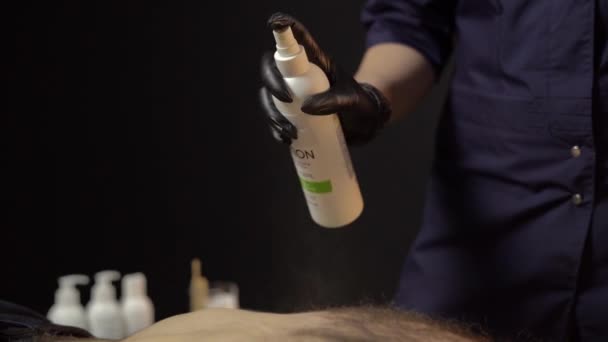 Mistrz depilacji nakłada specjalny balsam na męskie ciało przed zabiegiem. Koncepcja piękna i troski o męskie ciało — Wideo stockowe