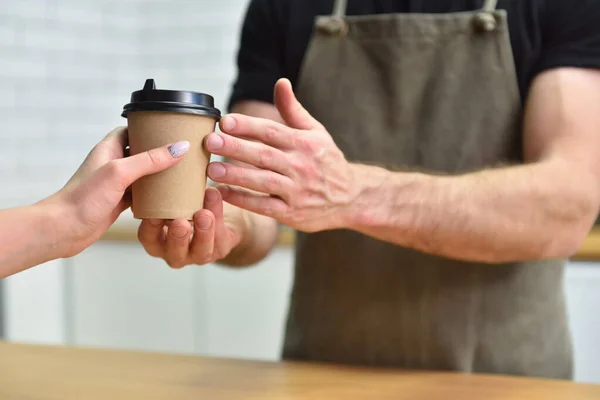 The bartender gives the customer coffee in a paper Cup, hands close-up.