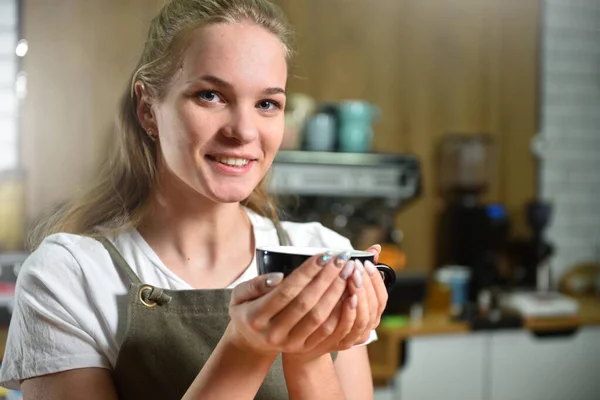Egy Fiatal Barista Lány Egy Kávésbögrét Tart Kezében Szünetben Mosolyog — Stock Fotó
