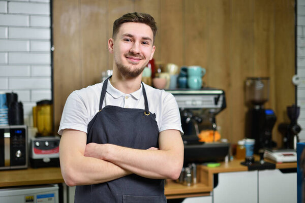 Young guy bartender barista on the background of a coffee machine in a coffee shop.